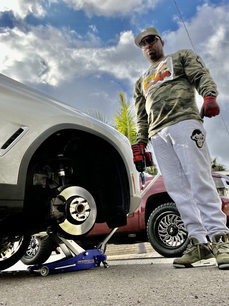 Technician changing a flat tire roadside in San Diego